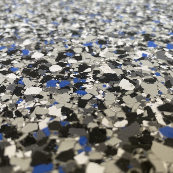 The image shows a close-up of a speckled surface with black, white, and blue flakes, possibly a terrazzo floor or a textured material.