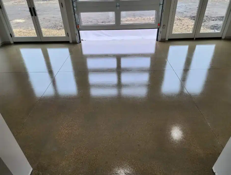 This is an indoors image showing a polished floor with the shadow of a large window cast on it, leading to a pair of closed glass doors.